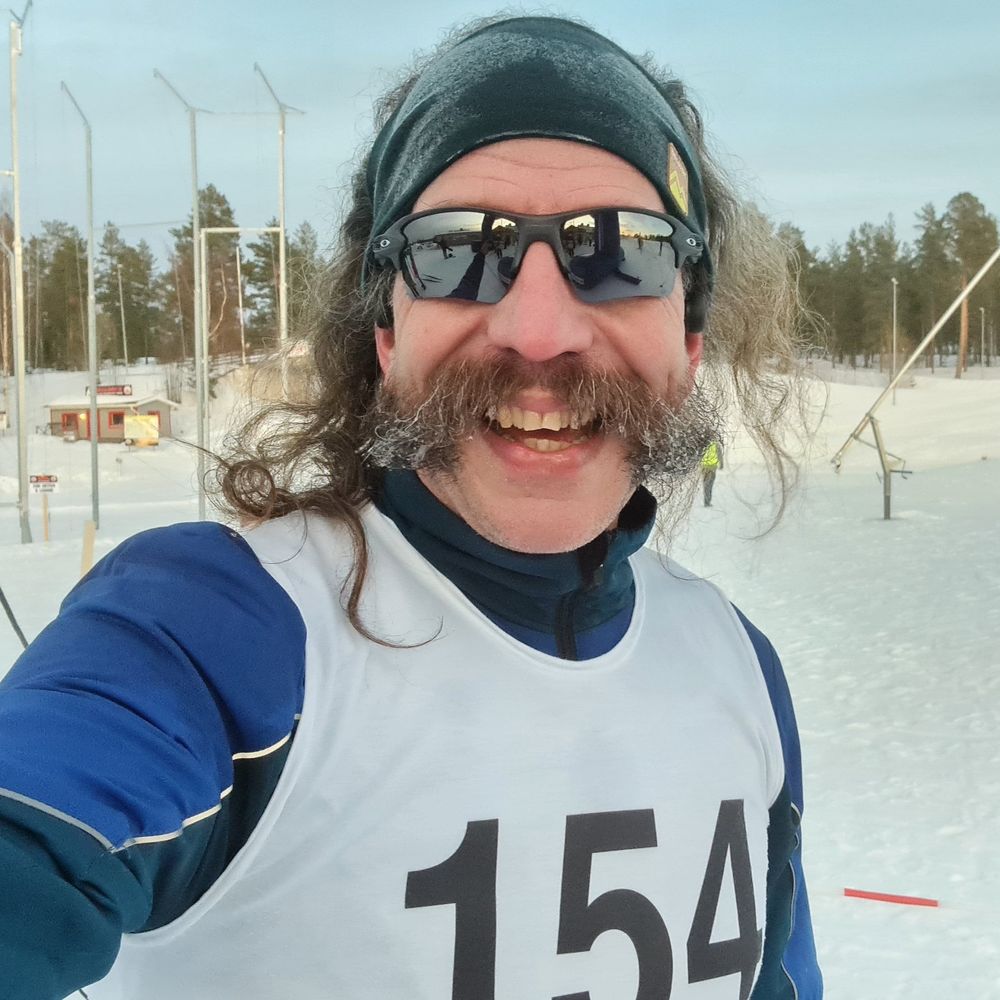 En brett leende man med nummerlapp på bröstet tar en selfie