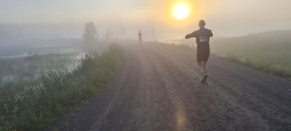 Soluppgång i dimma, med en löpare i förgrunden