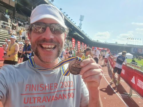 Glad löpare håller upp medalj för Stockholms marathon