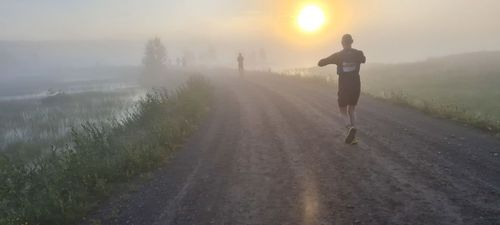 Soluppgång i dimma, med en löpare i förgrunden